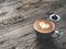 Heart love Latte art coffee in black cup on  vintage wooden table.