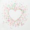 Heart love symbol made of colorful bright confetti on white background. Flat lay, top view copy space.