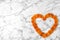 Heart made of apricots on marble background, top view with space for text.