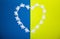 heart made of cut paper angels on a yellow-blue background in colors of Ukrainian flag