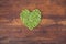 Heart made of fresh locally grown green peas on wooden background