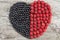 Heart made from fresh raspberries and blueberries on wooden background. Healthy nutrition