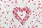 Heart Made from Multi-Colored Sugar Sprinkles Candies Scattered on White Stone Background. Valentine Romantic
