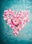 Heart made of pink rose petals on blue turquoise background, top view . Love , romantic and Valentines day