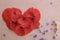 Heart made from red petals of poppy on a wooden background