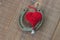 Heart made of red thread with a metal bell on an old worn horseshoe on boards