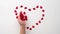 Heart made of shiny red small decorative hearts appearing on a white background with child hands