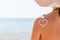 Heart made of sun cream is drawn on woman`s shoulder at the beach