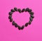 Heart made of watermelon seeds on bright pink background, love symbol