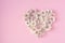 Heart made of  white small chrysanthemums on pink  background. Flat lay and top view photo