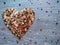 heart of multicolored spices, on a gray-blue wooden background sprinkled with coarse salt and pepper