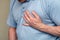 Heart pain, a person grabbing the heart area with his hand, suffering from chest pain, having a heart attack or painful