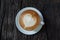 Heart patterned latte coffee on black wood floor.