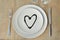 Heart on a plate. Wood table. Cutlery. Knife, fork. Glasses. Suitable as a background. For the menu. We love with love.