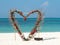 Heart from red flowers palm leafs on summer ocean beach background. Valentine, love, wedding concept. Clear sky, beautiful