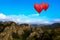 Heart shape ballooning flying over mountain