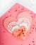 Heart shape cookie and paper hearts shaped cards on pink background