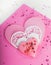 Heart shape cookie and paper hearts shaped cards on pink background