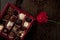 heart shape made from coffee beans and a box of chocolate pralines completed with red romantic rose on a table