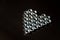 Heart shape made of hex bolts on dark grey background with reflection on left. Creative love concept
