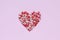 Heart shape made of a small heart shaped candy on pink background.