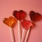 Heart shape red lollipop candy on pastel pink background. Minimal Valentine or love concept.