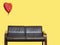 Heart shaped balloon tied to sofa over yellow background