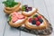 Heart shaped biscuits spread with quark, strawberries, blackberries, raspberries, cherries and a twig of mint presented on a tree