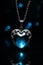 Heart shaped blue necklace pendant - silver chain - black background - blue glow - blue sapphire