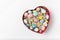 Heart shaped box with colorful holiday eggs. White background, top view. Happy Easter
