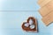 Heart shaped box with decorated Easter eggs and brown boards on wooden blue background. Spring nestlings, springtime and Easter