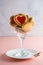 Heart-shaped cookies with jam filling in a martini glass on a pink plain background. Valentine\\\'s day concept
