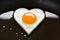 Heart shaped egg in a frying pan