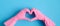 Heart shaped hands in pink rubber gloves over blue background. House cleaning service and housekeeping concept