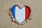 Heart shaped hole torn through paper, showing French flag