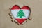 Heart shaped hole torn through paper, showing Lebanese flag