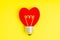 Heart shaped lightbulb symbol on yellow background