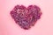 Heart shaped lilac flowers on pink background. Love symbol. Top view.