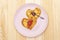 Heart shaped pancakes for romantic breakfast with strawberry jam and silver spoon. Shrovetide carnival concept. On wooden