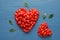 Heart shaped piles of fresh ripe goji berries on wooden table, flat lay