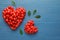 Heart shaped piles of fresh ripe goji berries on wooden table, flat lay