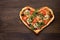 Heart shaped pizza with chicken and mushrooms on dark wooden vintage background.