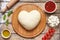 Heart shaped pizza cooking ingredients. Dough, mozzarella, tomatoes, basil, olive oil, spices. Work with the dough. Top