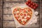 Heart shaped pizza margherita love food symbol with mozzarella, tomatoes, parsley, and garlic composition on cutting