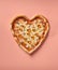 A heart shaped pizza on a pink background