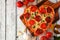 Heart shaped pizza for Valentines Day over white wood, above view, side border table scene