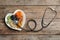 Heart shaped plate with nuts and dried fruits near stethoscope on wooden background