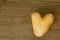 Heart shaped potato on old spruce wood board