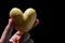 Heart shaped potato tuber Solanum Tuberosum held between thumb and finger of adult man, black background