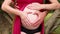 Heart shaped pregnancy. Hands of future parents cuddle, hugging and petting pregnant belly and making heart symbol on tummy.